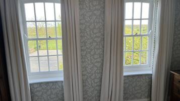 A room with two windows, each with a view of greenery outside.