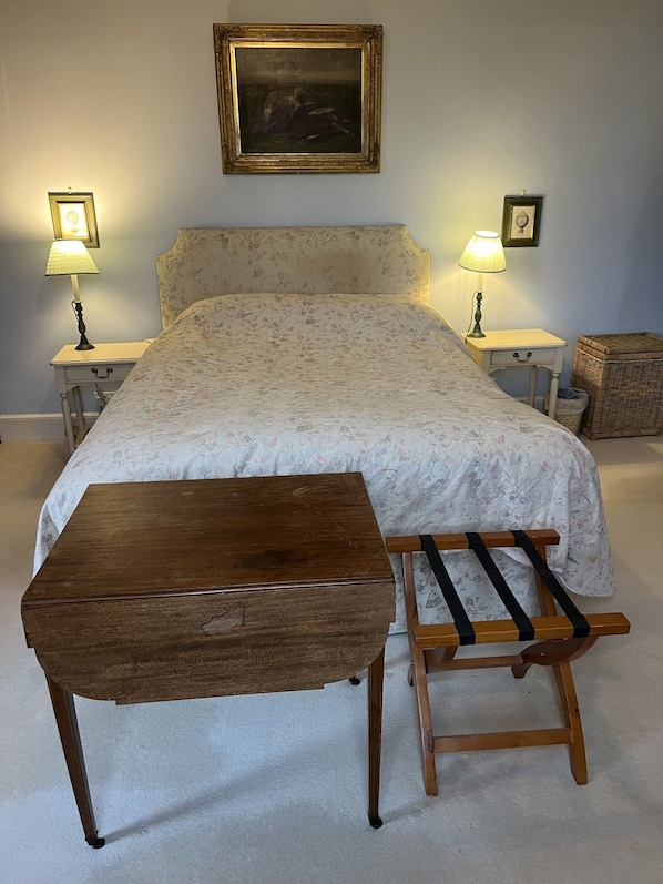 Een slaapkamer met een bed, nachtkastjes, een houten bankje en een schilderij aan de muur.