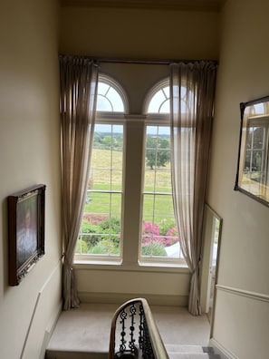 Een kamer met uitzicht op een tuin door een raam met gordijnen.