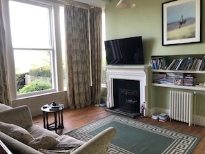 Een woonkamer met een open haard, een televisie en een boekenkast.