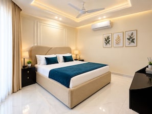 A modern bedroom with a large bed, bedside lamps, a ceiling fan, and wall-mounted air conditioning.