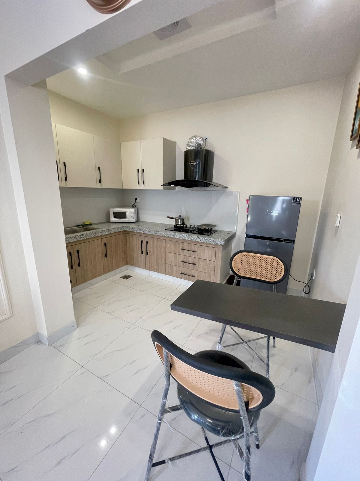 Cocina compacta equipada con microondas, estufa y refrigerador. Cuenta con una mesa de comedor y sillas.