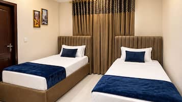 A hotel room with two beds, a ceiling fan, and a window with curtains.