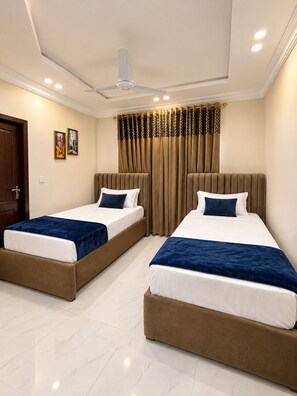 A hotel room with two beds, a ceiling fan, and a window with curtains.