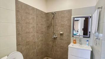 A bathroom with a shower, toilet, and vanity.
