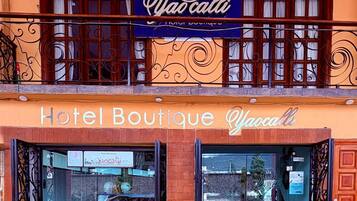Een boetiekhotel met een bord waarop staat 'Hotel Boutique Yao cali' en een balkon met decoratieve leuningen.