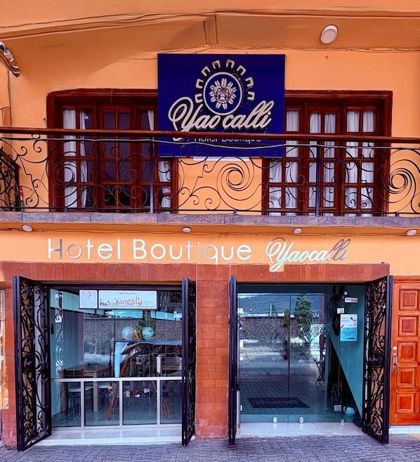 Un hotel boutique con un letrero que dice "Hotel Boutique Yao cali" y un balcón con barandillas decorativas.