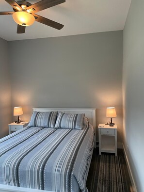 A bedroom with a bed, two bedside tables, a ceiling fan, and a rug. - Serene & cozy 3-bedroom house in charming Denison (Denison)