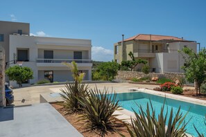 A modern residential complex with a swimming pool, multiple balconies, and a stone wall. - Le Mont Blanc | 2-Bedroom Apartment with Shared Pool (Kounoupidiana)