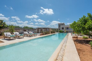A swimming pool with lounge chairs, a small building, and a modern house in the background. - Le Mont Blanc | 2-Bedroom Apartment with Shared Pool (Kounoupidiana)
