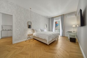 A modern bedroom with a herringbone wood floor, a bed with white bedding, a bedside table, a mirror, and a small round table. - Apartment 'Luxury Apartment Toledo White' with Balcony, Wi-Fi and Air Conditioning (Napoli)