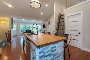 A kitchen with a wooden island, a built-in stove, and a large window.