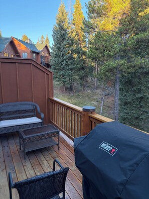 A deck with wicker furniture and a grill cover. - Perfect 3-bedroom condo in Big Sky for your next getaway with relaxing hot tub (Big Sky)