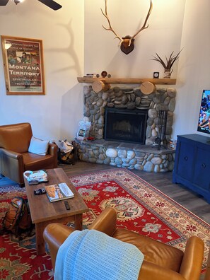 Un salon chaleureux avec une cheminée en pierre, des meubles en cuir et un élément décoratif mural.