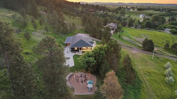 Una casa con un amplio patio, rodeada de árboles y un paisaje montañoso.