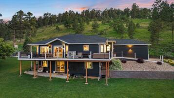 A two-story house with a deck, large windows, and a well-maintained lawn.