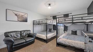 Een kamer met stapelbedden, een leren bank en een lijst aan de muur.