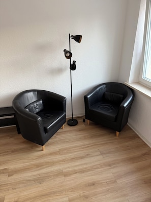 A room with two black leather armchairs, a floor lamp, and a wooden floor. - Central Location in Wolfsburg (Wolfsburg)
