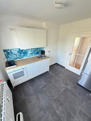 A compact kitchen with a built-in oven, a sink, and a refrigerator. - Central Location in Wolfsburg (Wolfsburg)