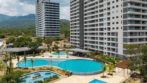 A hotel with multiple swimming pools, surrounded by lush greenery and mountains in the background. - Balcon del Mar - Family-Friendly Apartment with a Balcony and Ocean View (Santa Marta)