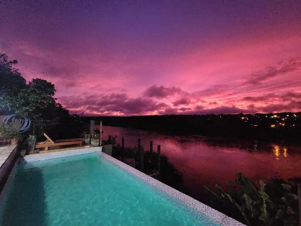 A swimming pool with a view of a body of water and a sunset sky.