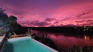 A swimming pool with a view of a body of water and a sunset sky.