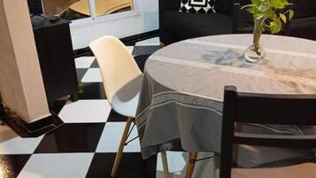 A dining area with a checkered floor, a round table with a tablecloth, and a black and white patterned sofa.