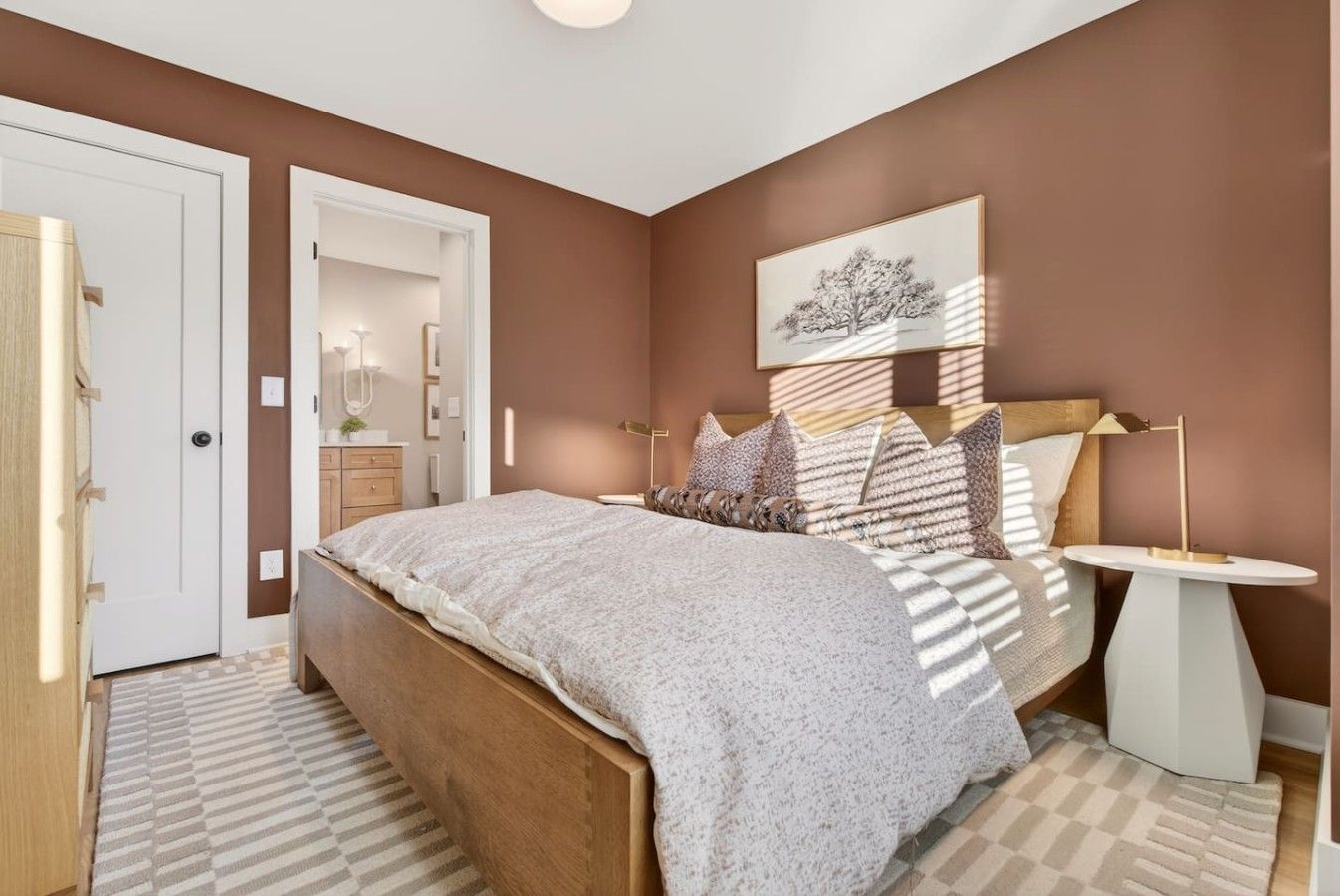A bedroom with a bed, bedside tables, a nightstand, a wall-mounted lamp, and a door.