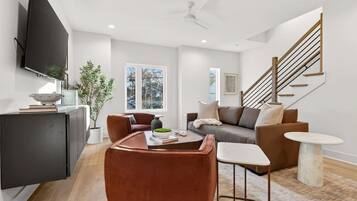 A modern living room with a sofa, coffee table, and a TV mounted on the wall.
