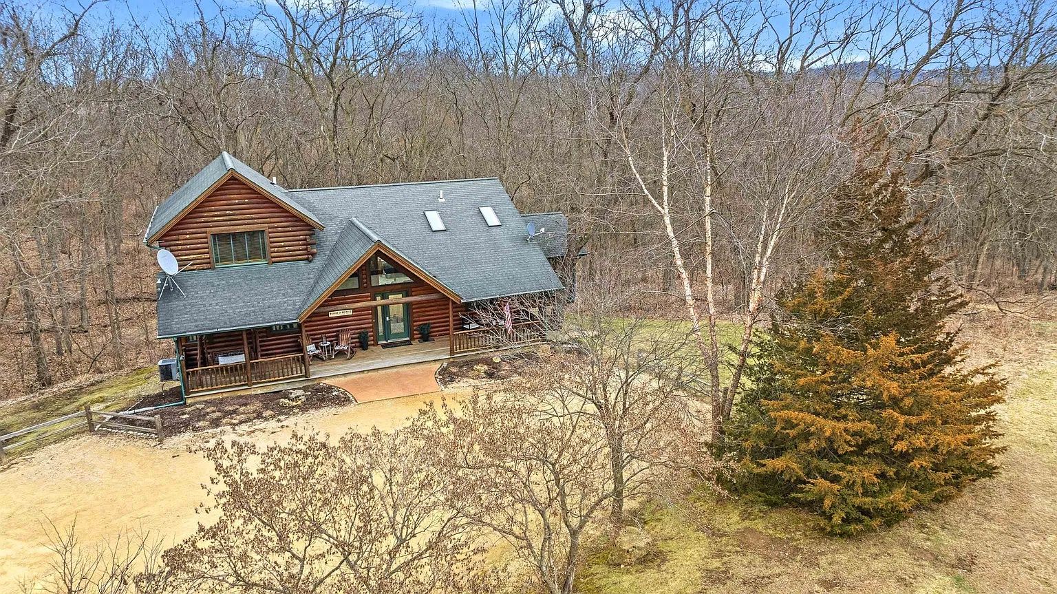 A cabin with a porch, satellite dishes, and a view of the surrounding forest.