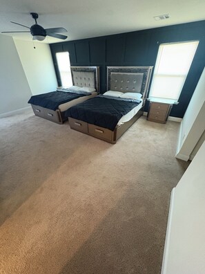 A bedroom with two beds, a ceiling fan, and a window with blinds. - The Wayne House - Spacious 4BR Retreat Near PGA Frisco & Universal (Aubrey)