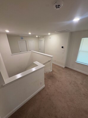 Ein Zimmer mit Teppichboden, weißen Wänden und einer Decke mit Einbaustrahlern.