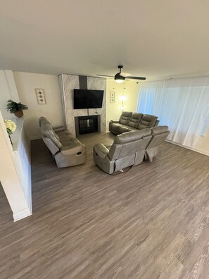 A living room with a fireplace, a flat-screen TV, and a ceiling fan. - The Wayne House - Spacious 4BR Retreat Near PGA Frisco & Universal (Aubrey)