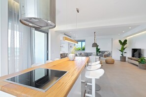 Eine moderne Küche mit integriertem Induktionskochfeld, einer Holz Arbeitsplatte und einem großen Fenster mit transparenten Vorhängen.