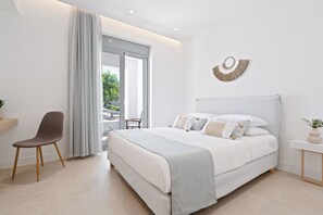 Ein modernes Schlafzimmer mit einem großen Bett, einem Sessel und Blick ins Freie.