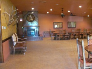 Ein Restaurant-Interieur mit Kamin, Holzsesseln und Tischen.