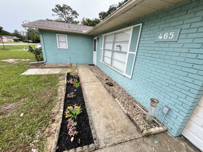 A residential house with a number 465 sign, a front yard with a flower bed, and a driveway. - Spacious 4-bedroom house in the enchanting Silver Springs Shores (Ocala)