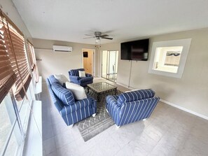 A living room with a sectional sofa, a chair, a coffee table, and a television mounted on the wall. - Spacious 4-bedroom house in the enchanting Silver Springs Shores (Ocala)