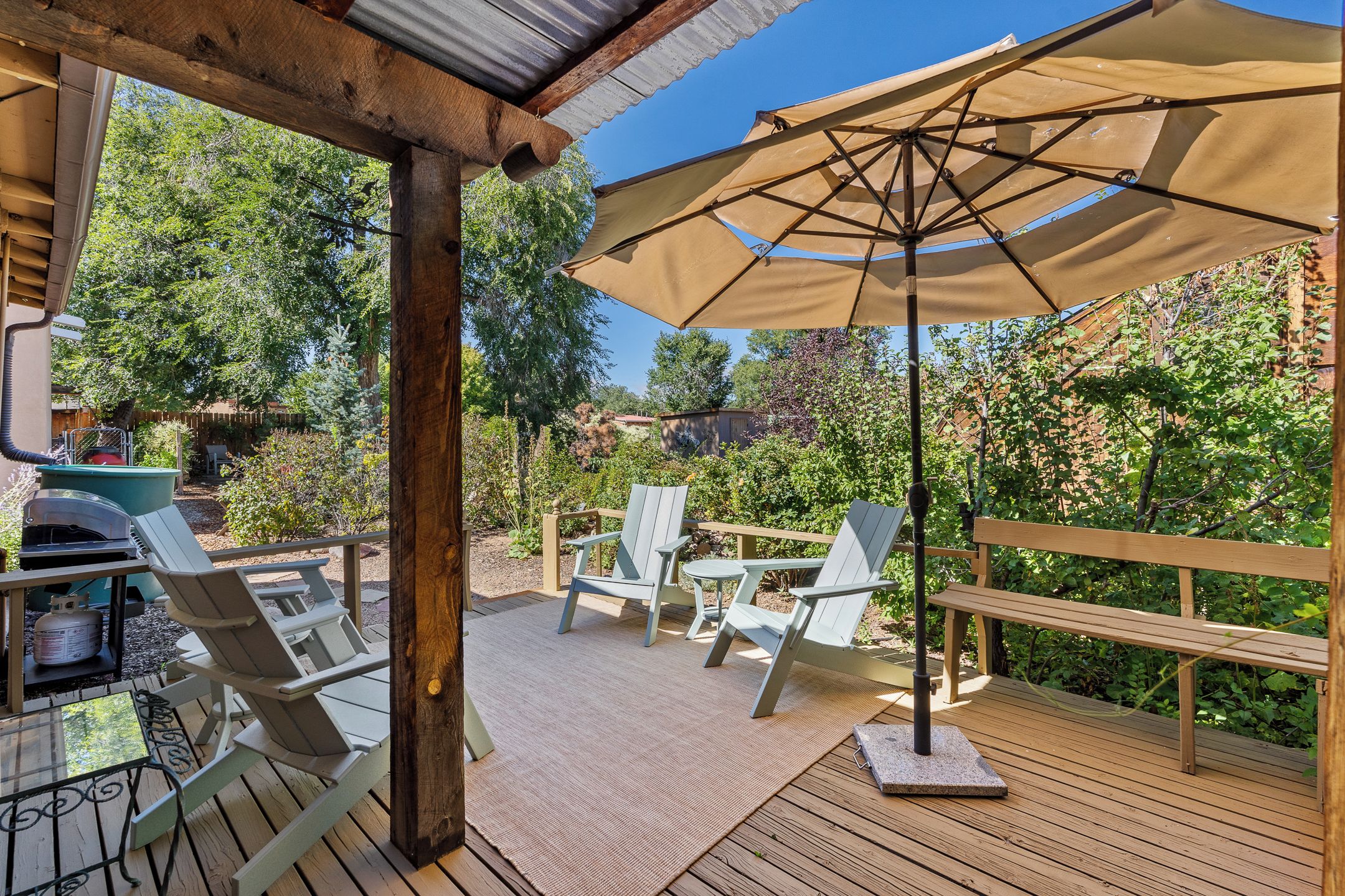 An outdoor patio with a grill, seating area, and a pergola with an umbrella.
