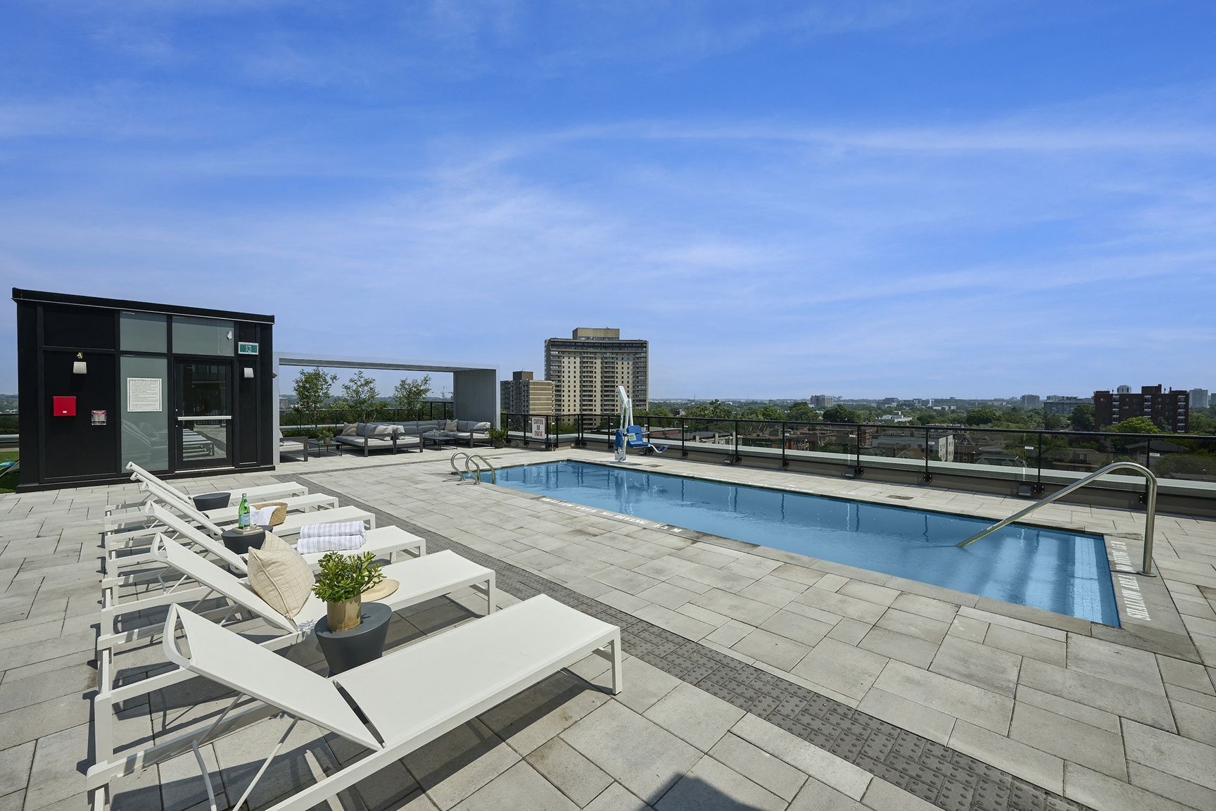 A rooftop pool area with lounge chairs and a small building.
