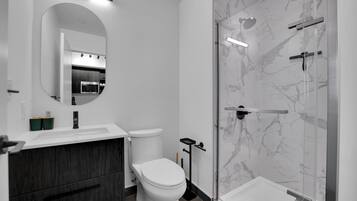 A modern bathroom with a toilet, sink, and shower.