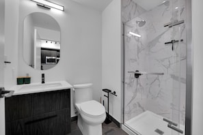 A modern bathroom with a toilet, sink, and shower.