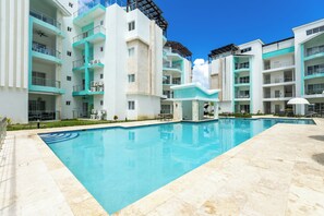 A modern hotel with a swimming pool, multiple balconies, and a clear blue sky. - Apartment with a Pool Just Steps from the Beach and Restaurants, Central Location (Punta Cana)