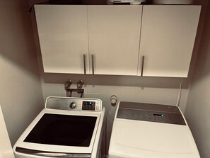 A laundry area with a washing machine and dryer, a cabinet above, and a control panel on the washing machine. - 3-bedroom house in amazing Albuquerque with cool patio for fall nights (Albuquerque)