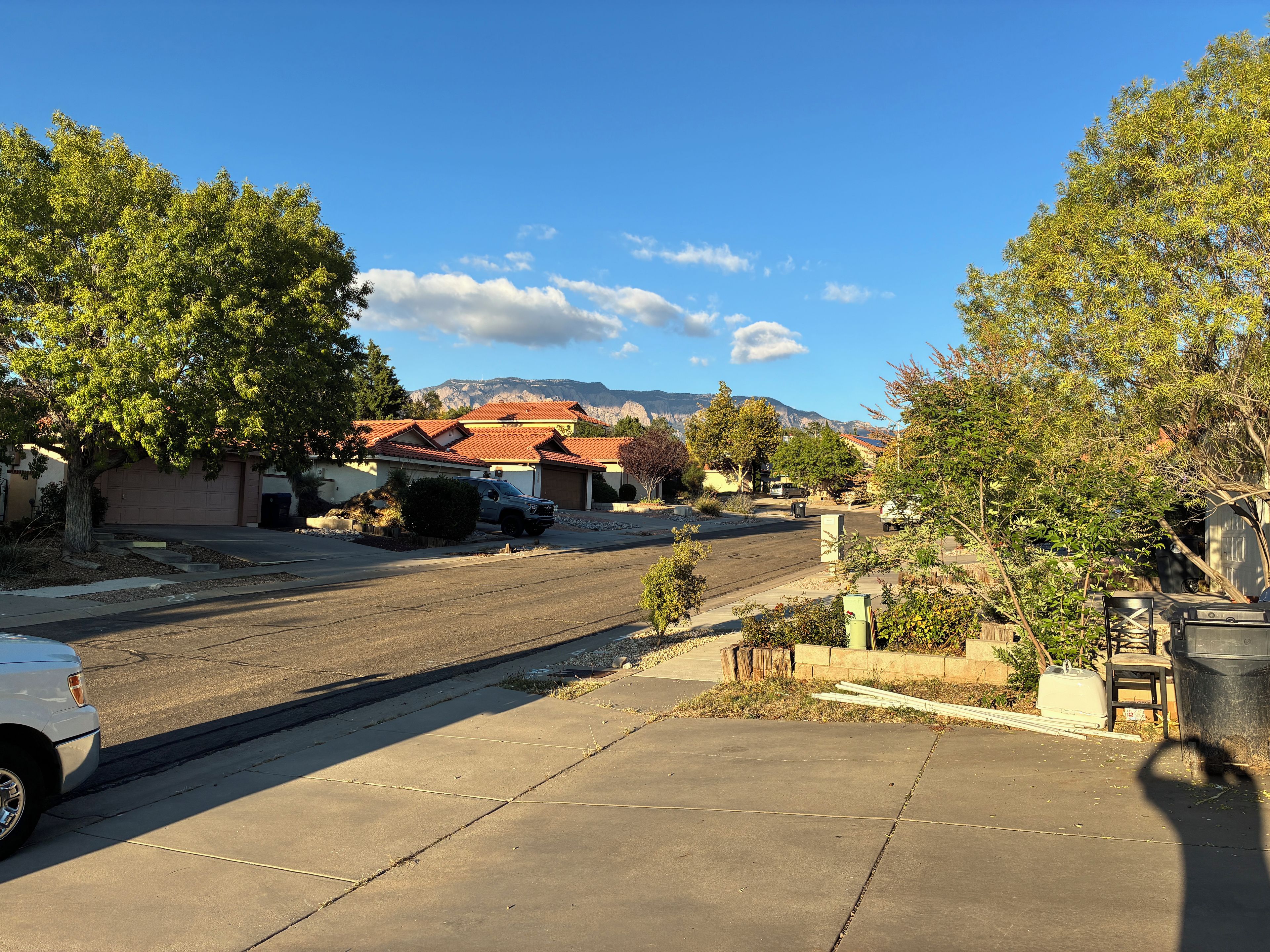 A residential street with houses, a parked SUV, and a mountain in the background.