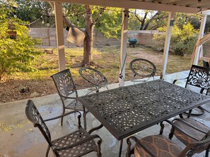 An outdoor patio with a metal table and chairs, surrounded by a wooden pergola and string lights. - 3-bedroom house in amazing Albuquerque with cool patio for fall nights (Albuquerque)
