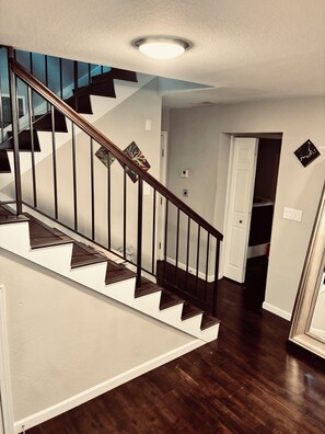Una escalera de madera con barandal y escalones oscuros que conducen a una plataforma.