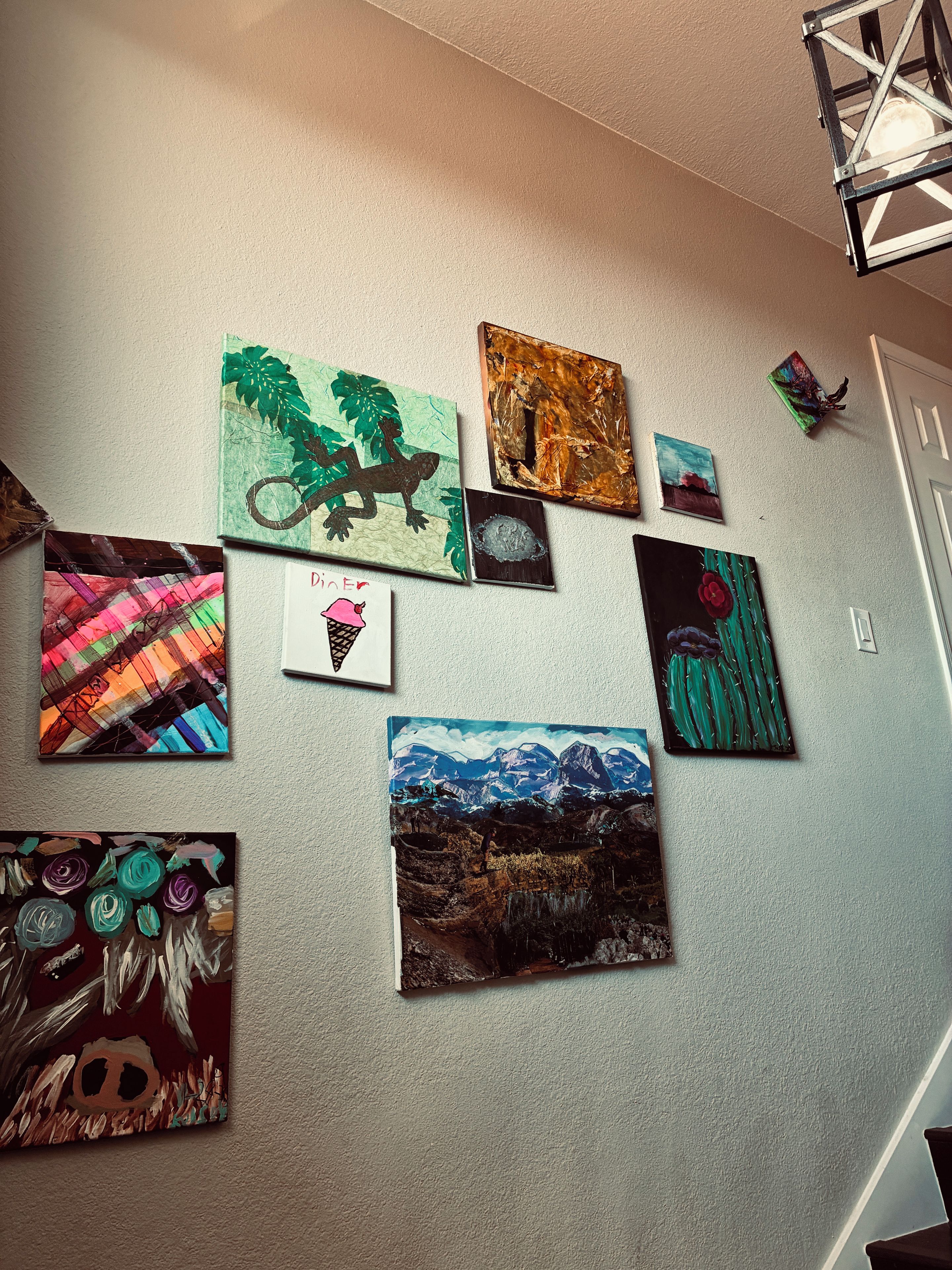 A wall with various artworks and a small sign.