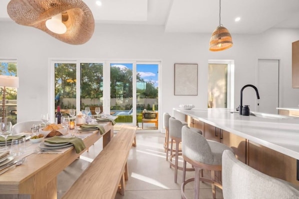 A modern kitchen with a large island, dining area, and large windows.