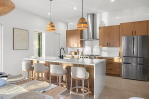 A modern kitchen with a central island, stainless steel appliances, and wooden cabinets.
